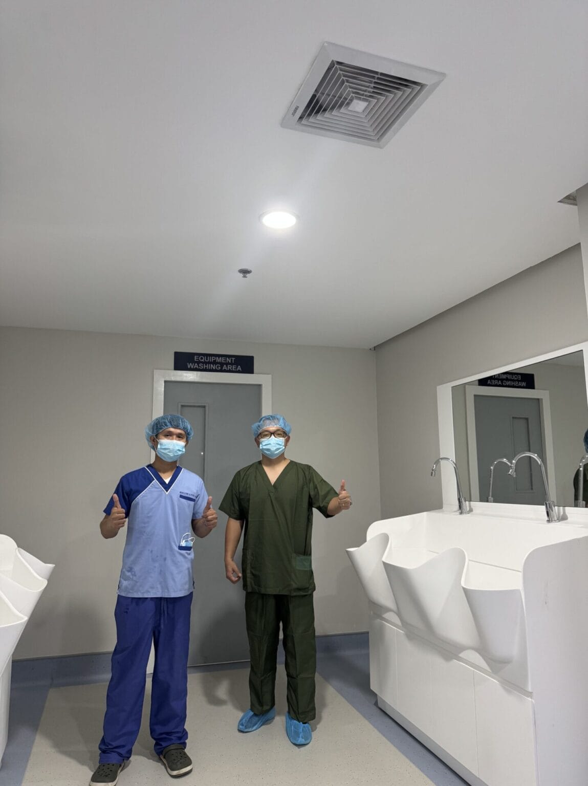 Two staff members standing beside the solid surface surgical sink at JBLMGH, Philippines