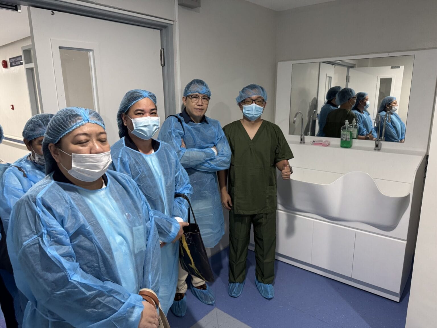 Clinicians giving a thumbs-up beside the solid surface surgical sink at JBLMGH, Philippines
