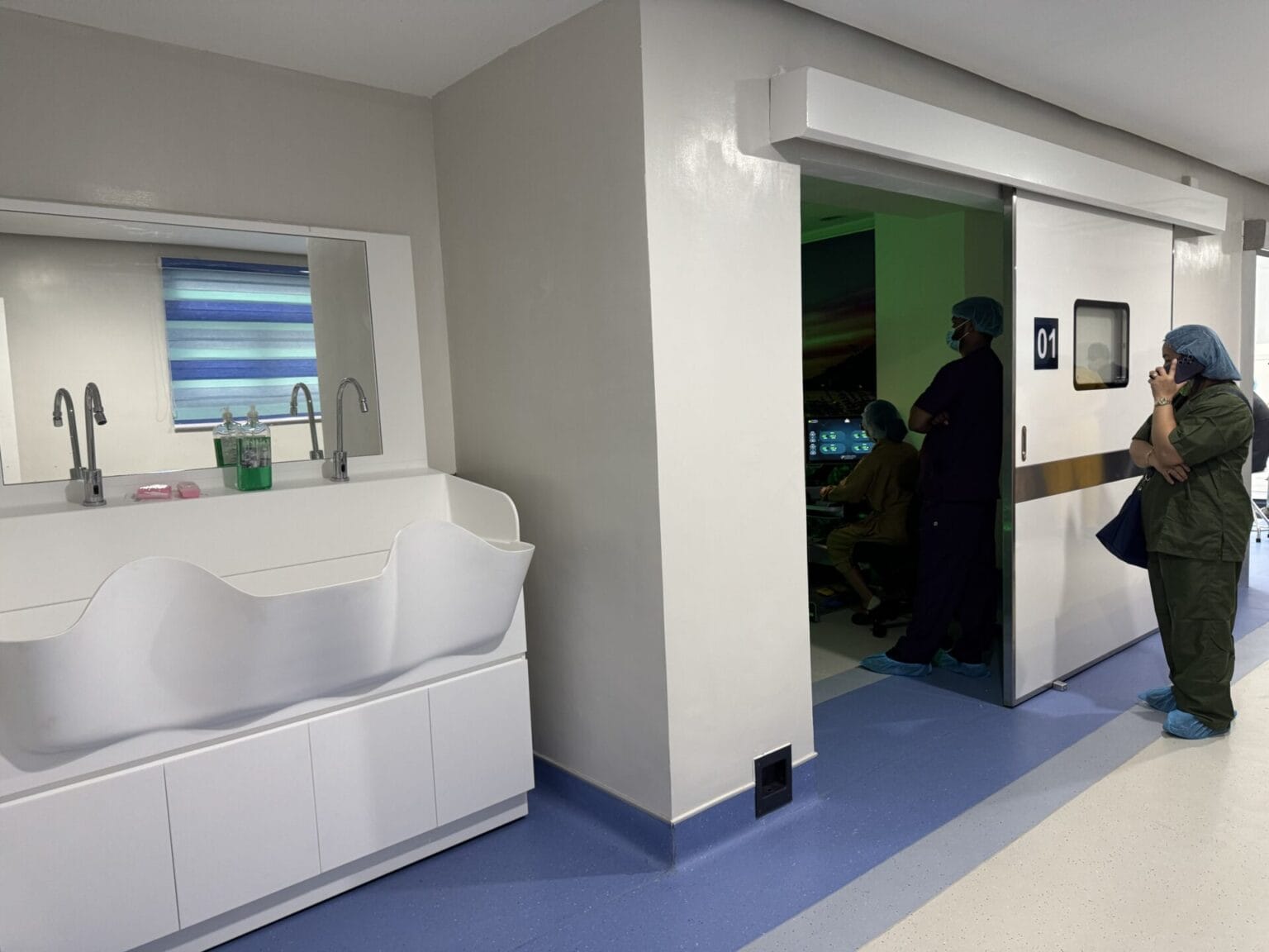 Curved solid surface surgical sink with sensor taps beside a hermetic door to operating room 01 at JBLMGH