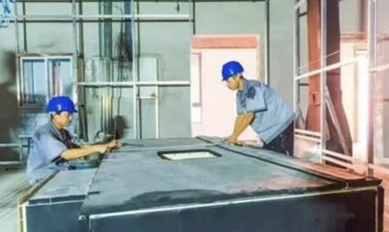 Two workers assembling industrial equipment indoors.