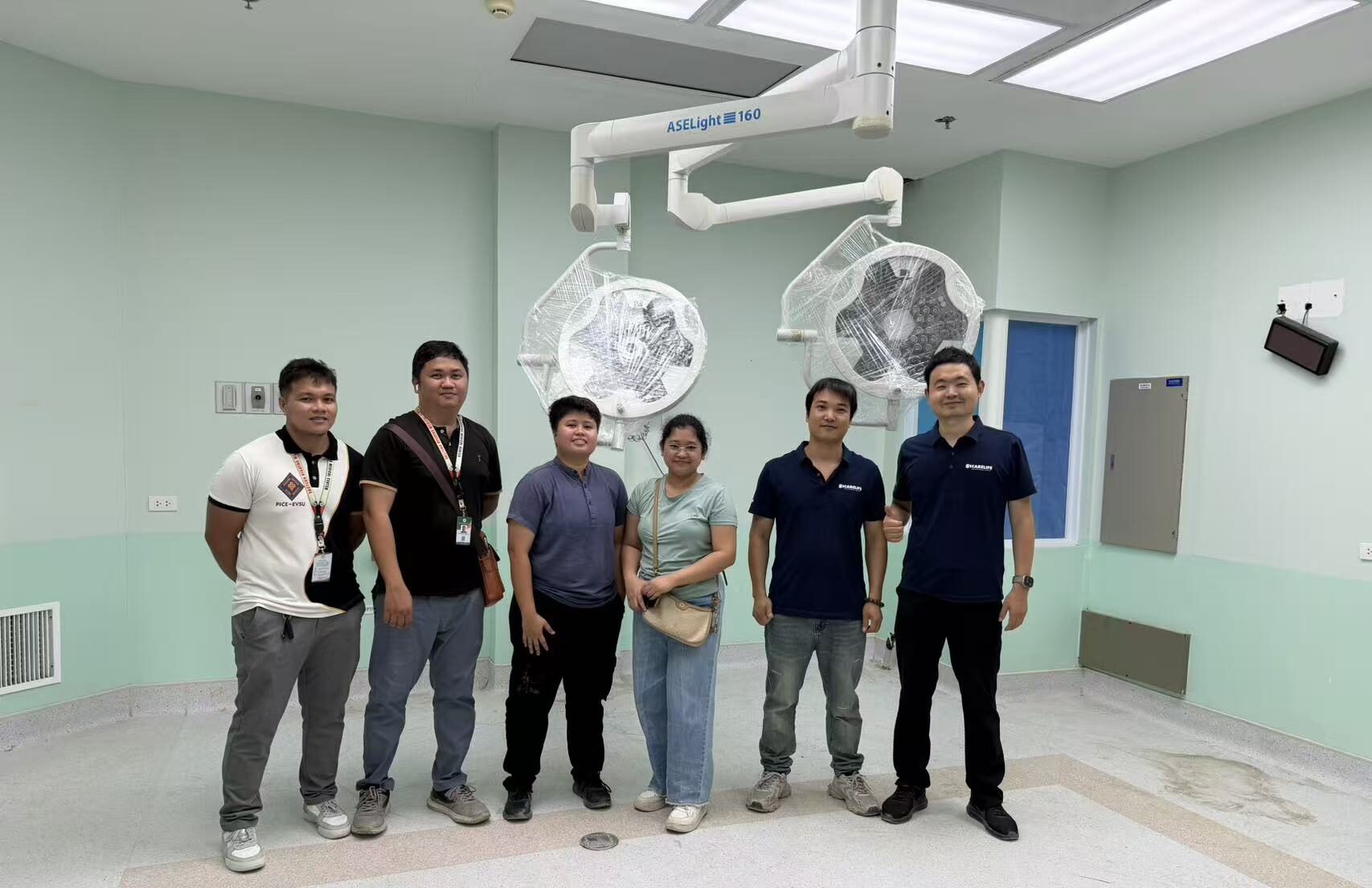 ICARELIFE team conducting pre-installation check inside an operating room with surgical lights still in protective wrapping